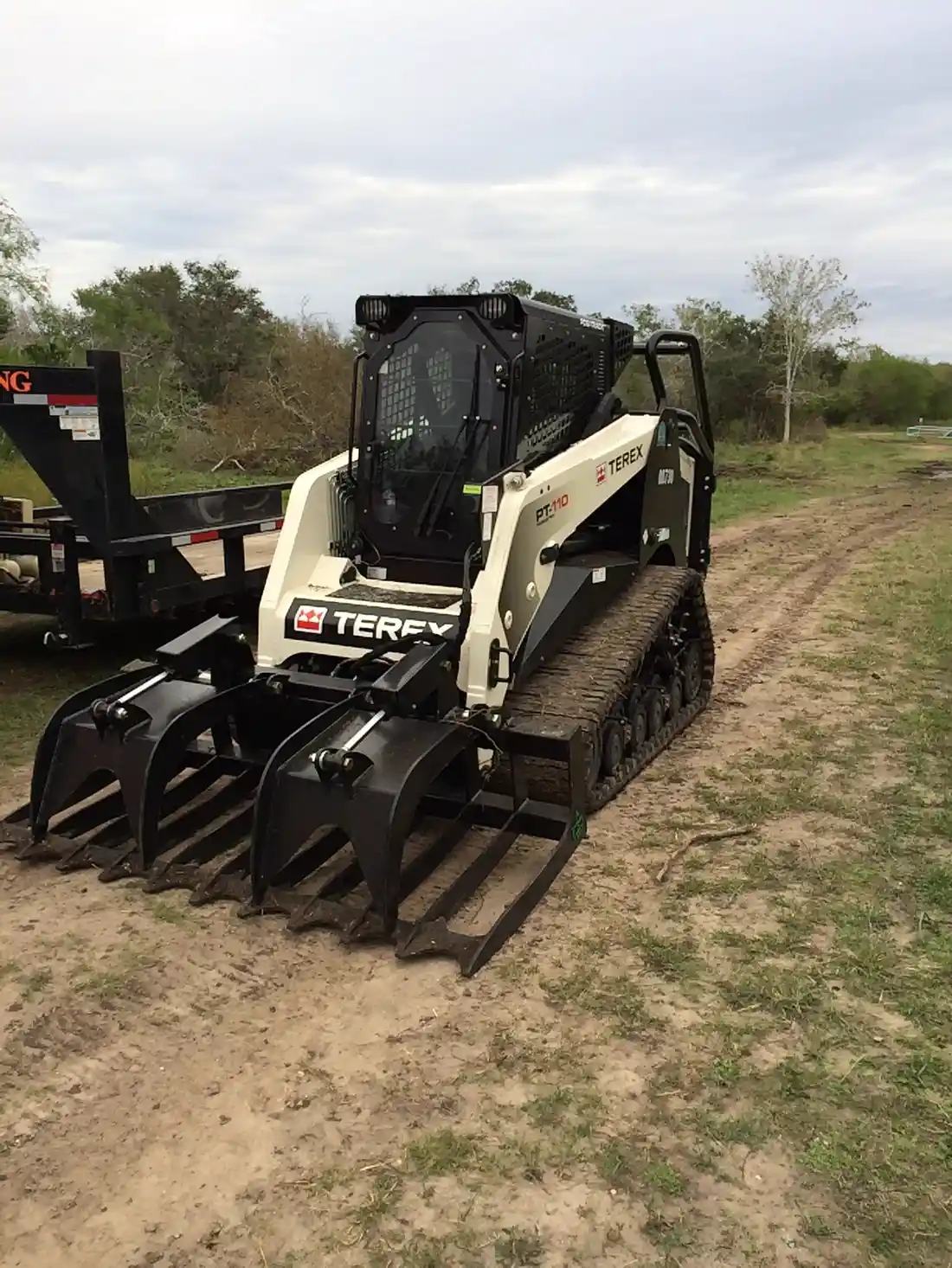 Tracked skid steer with grapple attachment on site